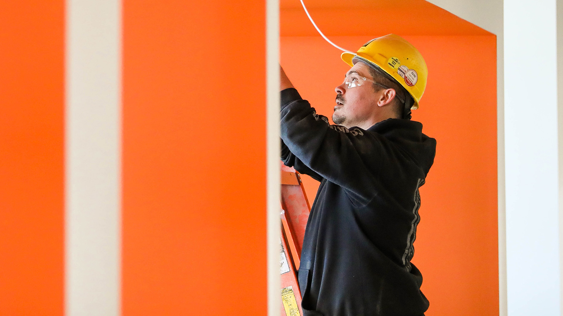 A Commonwealth employee works overhead on Low Voltage work