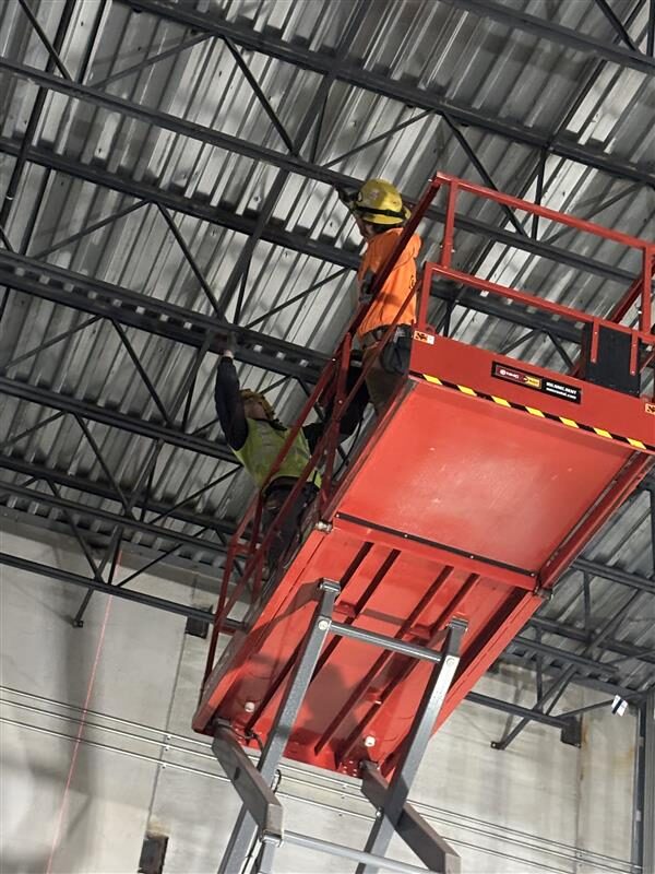 A picture of two employees working on a lift.